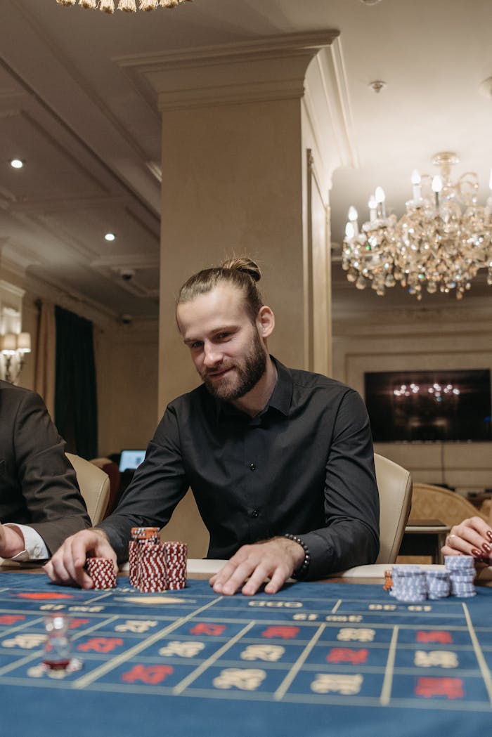 Offerings A man with a beard playing poker at a casino, focused on the game with poker chips on the table.