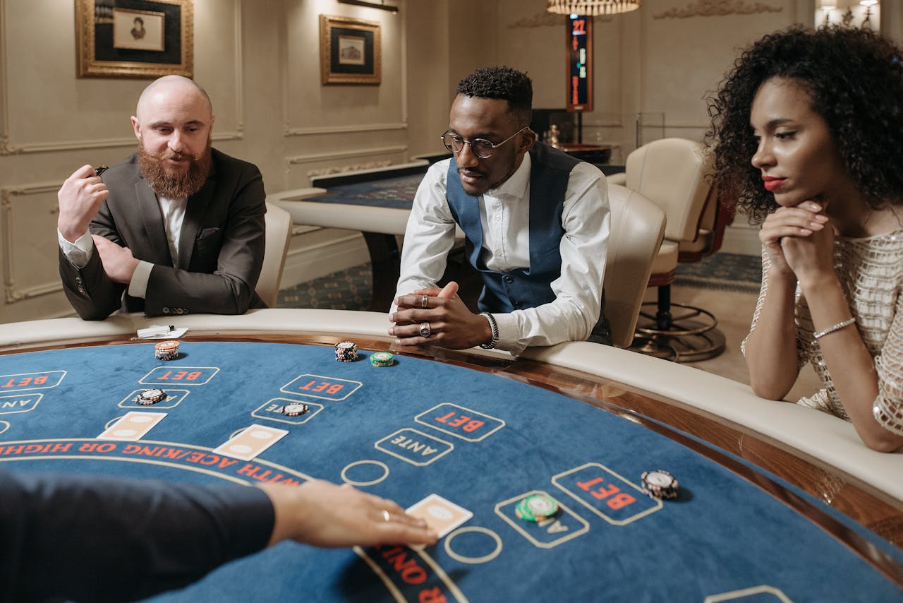 Offerings Diverse group of adults engaged in a game at a casino table, focusing intently.